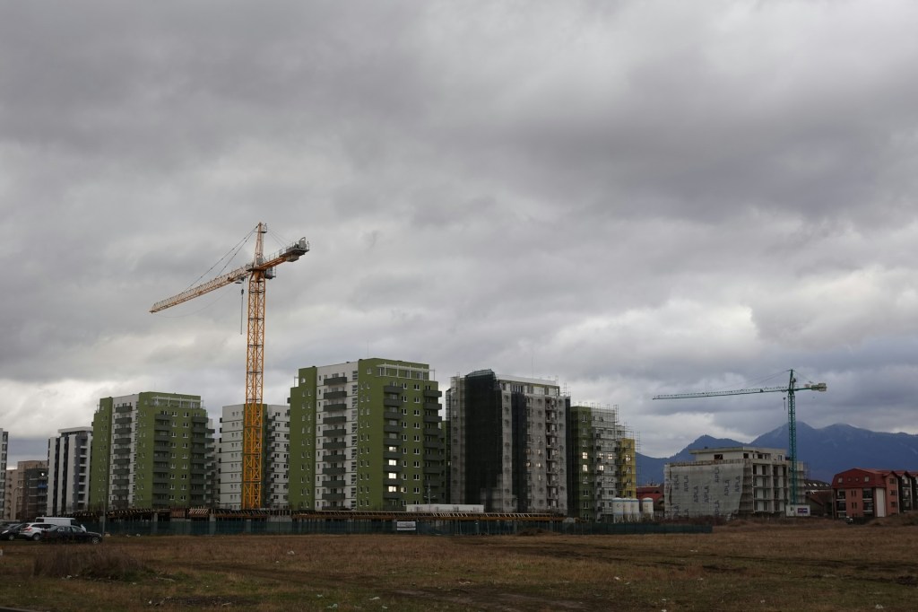 A construction site, seen from the side a few hundred meters away. Dark clouds above.