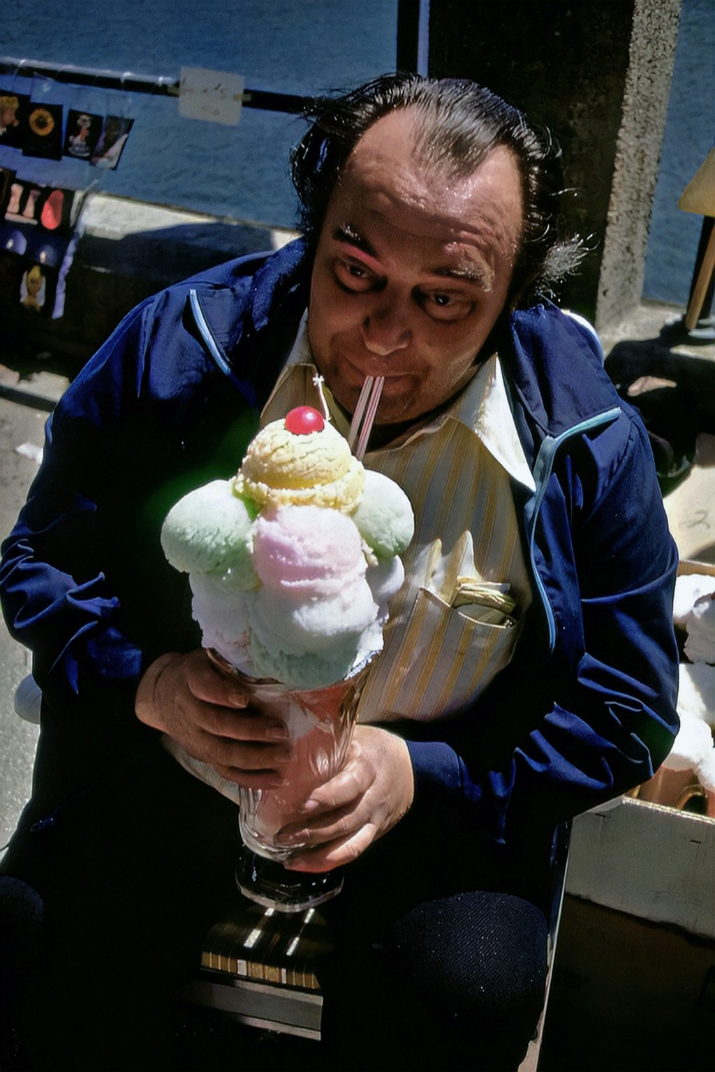 A picture illustrating greed. A man eating an enormous icecream on a cone, with a straw.